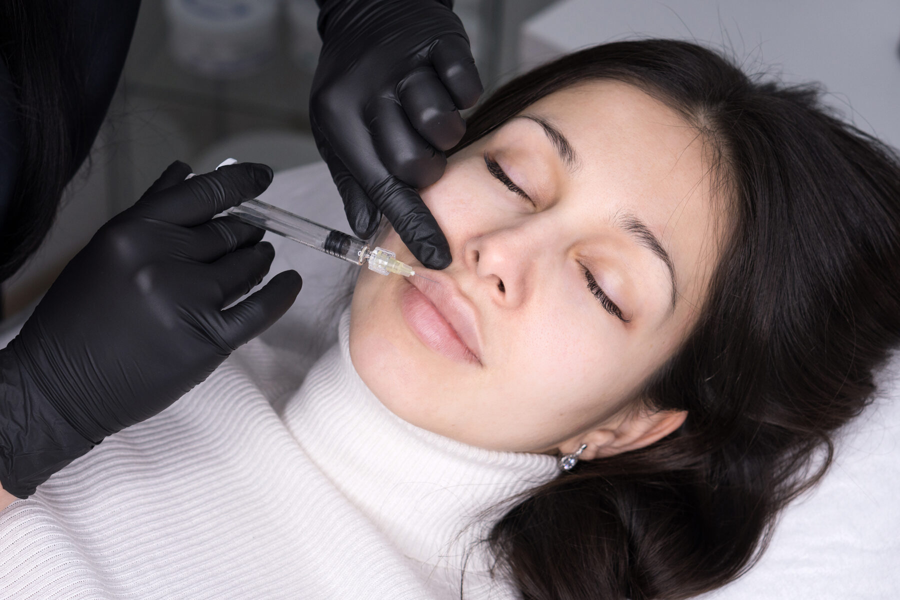 A nurse practitioner assessing facial structure before dermal filler treatment at Pulse Health & Wellness